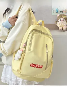 Detail view of yellow nylon backpack with Hokeam logo and cute plush bear charm