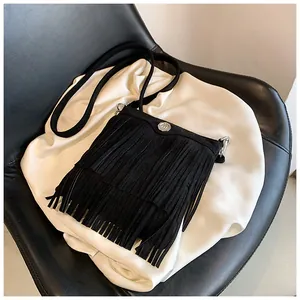 Detail view of black faux suede fringe crossbody bag with silver logo and metal hardware