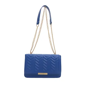Blue quilted faux leather crossbody bag with V-shaped stitching and gold chain strap