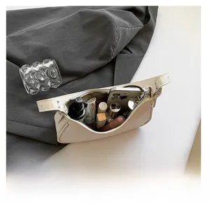 Internal capacity detail showing phone and makeup in white crescent shoulder bag