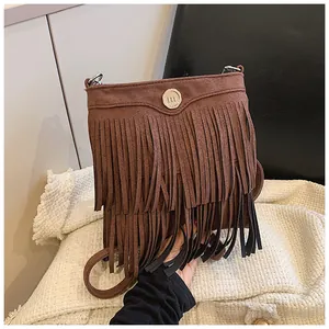 Close-up of brown suede tassel crossbody bag featuring a golden metallic M logo buckle