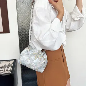 Detail der hellblauen Tasche mit Schmetterlingsstickerei, Perlengriff und Kette