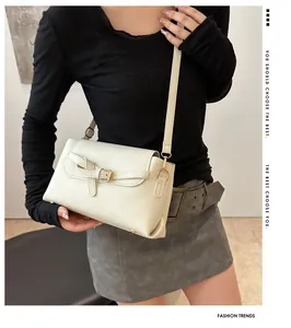 Detailopname van een crème lederen crossbodytas met gouden gesp op een model