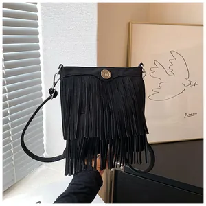Detail of black fringe crossbody bag with gold logo emblem and suede texture