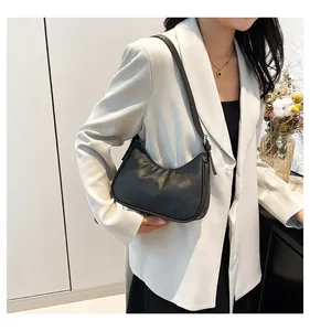Chic black hobo bag with matte texture worn on white suit for minimal style