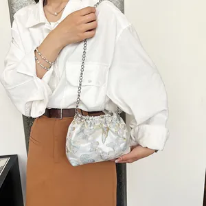 Detail der blauen Satin-Beuteltasche mit Schmetterlingsstickerei und großem Perlengriff