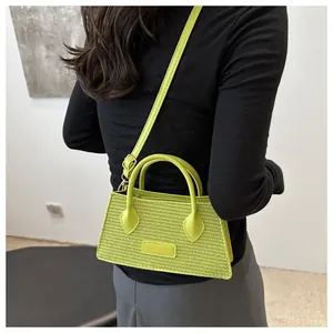 Detail of neon green woven crossbody bag featuring adjustable strap and fashion label