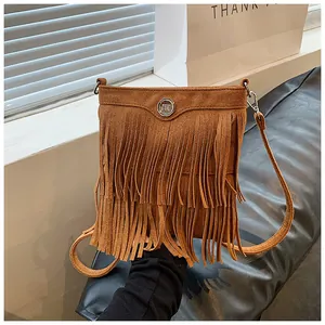Detail of bohemian brown faux suede bag featuring long fringe tassels and metal logo