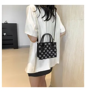 Détail de la texture d'un sac à damier noir et gris porté par un mannequin chic