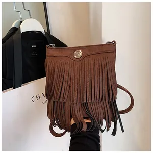 Detail of a brown fringe crossbody bag showing high-quality suede texture and metal accent