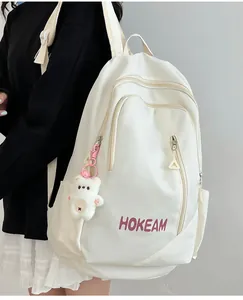 Detail of white nylon backpack with HOKEAM logo and cute bear plush charm attached