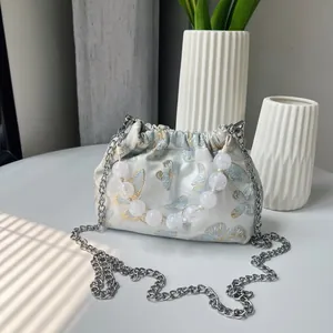 Detail aus blauem Schmetterlings-Jacquard-Stoff mit Perlengriff und silberner Kette