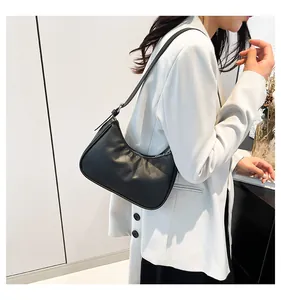 Detail of black crescent shoulder bag with woven texture on white blazer model