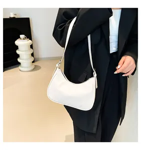 Close-up of minimalist white crescent underarm bag worn on shoulder with black blazer