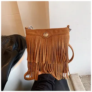 Detailed macro view of the brown suede fringe and retro gold circular metal buckle