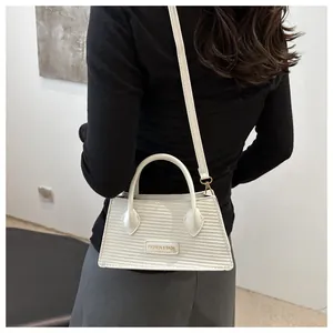 Detailed view of white woven texture crossbody bag with adjustable gold hardware strap