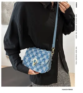 Détail d'un sac à carreaux en denim avec bords effilochés et boucle métallique texturée