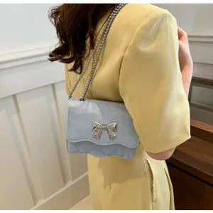 Macro detail of the light blue crossbody bag with silver bow clasp and chain strap