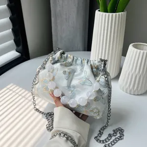 Detail der hellblauen Satin-Beuteltasche mit Schmetterlingsstickerei und Perlengriff