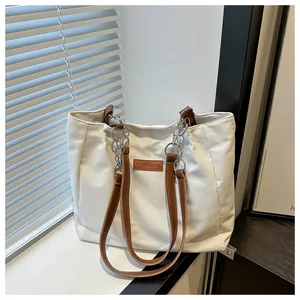 Detail of canvas tote bag with leather handle and metal chain linkage mechanism