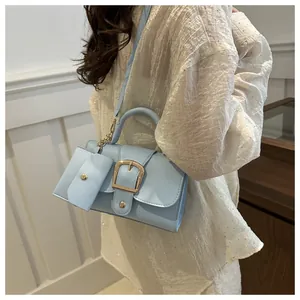Light blue PU leather handbag with gold buckle and mini pendant on a white sequin top
