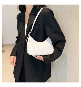 Close-up of white crescent shoulder bag with fine leather texture and metal buckle detail