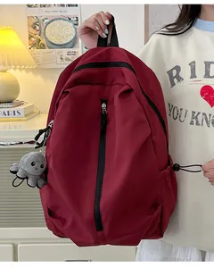 Detail eines burgunderroten Nylon-Rucksacks mit Reißverschluss und Oktopus-Anhänger