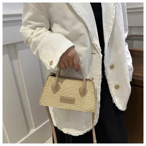 Detail of minimalist beige woven straw handbag with leather handles and embossed label