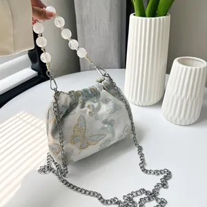 Detail der Stickerei und des Perlengriffs an einer weißen Beuteltasche im China-Stil