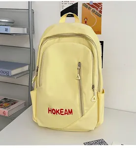 Detail of light yellow backpack showing HOKEAM print and multiple zipper pockets