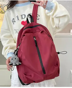 Detail eines burgunderroten Nylon-Rucksacks mit vertikalem Reißverschluss und Oktopus-Anhänger