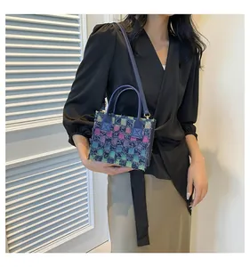 Détail d'un petit sac carré en tweed à carreaux colorés avec poignées en cuir marine