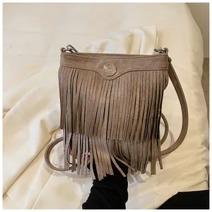 Detail of vintage brown suede crossbody bag with long tassels and metallic logo