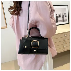 Detail of a black crossbody box bag with gold buckle and a small matching side pouch