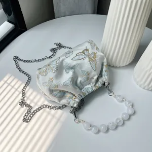 Detaillierte Schmetterlingsstickerei auf Seiden-Beuteltasche mit elegantem Perlengriff