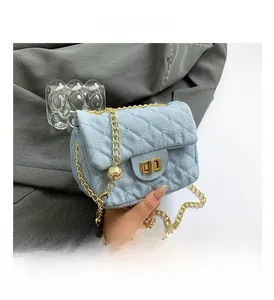 Detail of light blue quilted denim bag with gold chain strap and adjustable ball
