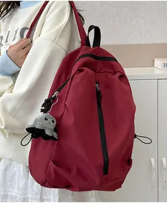 Detail eines burgunderroten Nylon-Rucksacks mit schwarzem Reißverschluss und Oktopus-Anhänger