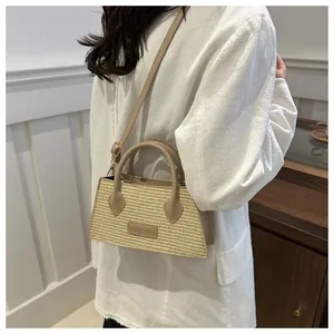 Detail of woven straw crossbody bag featuring premium leather handles and a fashion label