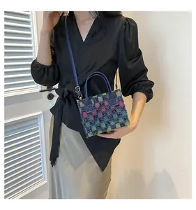 Détail du sac bandoulière en tweed à carreaux avec poignées en cuir bleu et sangle