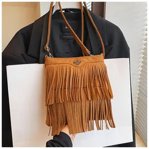 Close-up of brown suede crossbody bag featuring tiered long fringe and metal logo detail