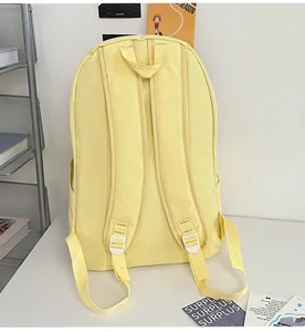 Rear view of light yellow nylon backpack with wide adjustable straps and side water bottle pocket