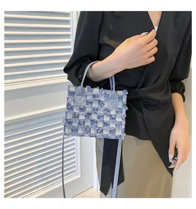Détail du sac à main à carreaux en jean bleu avec bords effilochés et anses