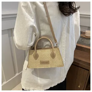 Detail of hand-woven straw tote with PU leather straps and branded label in casual style