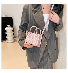 Close-up of pink mini crossbody bag with M-pattern jacquard and gold metal hardware