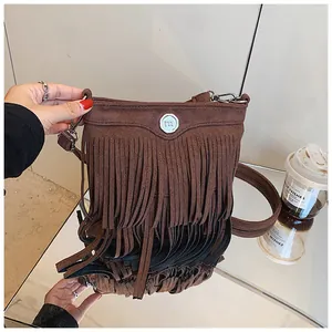 Detail of bohemian brown faux suede crossbody bag with long fringe and silver metal buckle