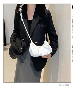 Detail of white pleated dumpling bag texture on model with elegant black suit