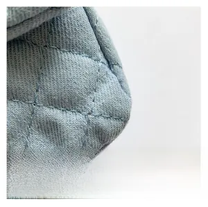 Detailed macro shot of light blue denim fabric with classic quilted diamond pattern