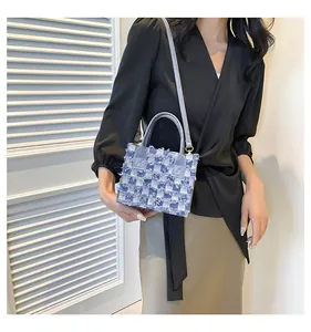Détail de la texture en denim bleu à carreaux et des bords effilochés du sac à main