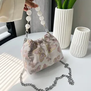 Detail der Schmetterlingsstickerei und Perlengriff an der eleganten Beuteltasche