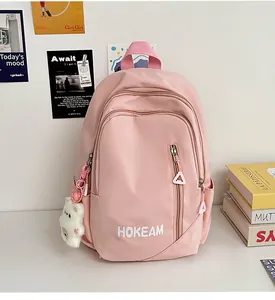 Pink waterproof nylon backpack with plush bear charm and multiple zip pockets
